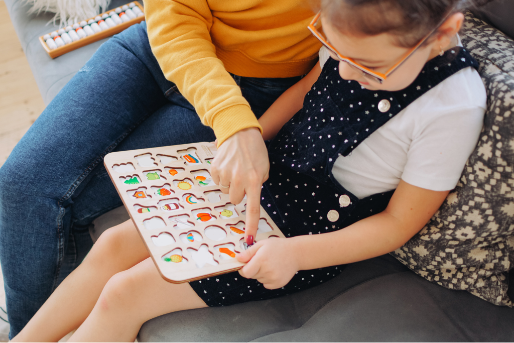 Homeschool mom and child working together on a letter puzzle to practice alphabet recognition.