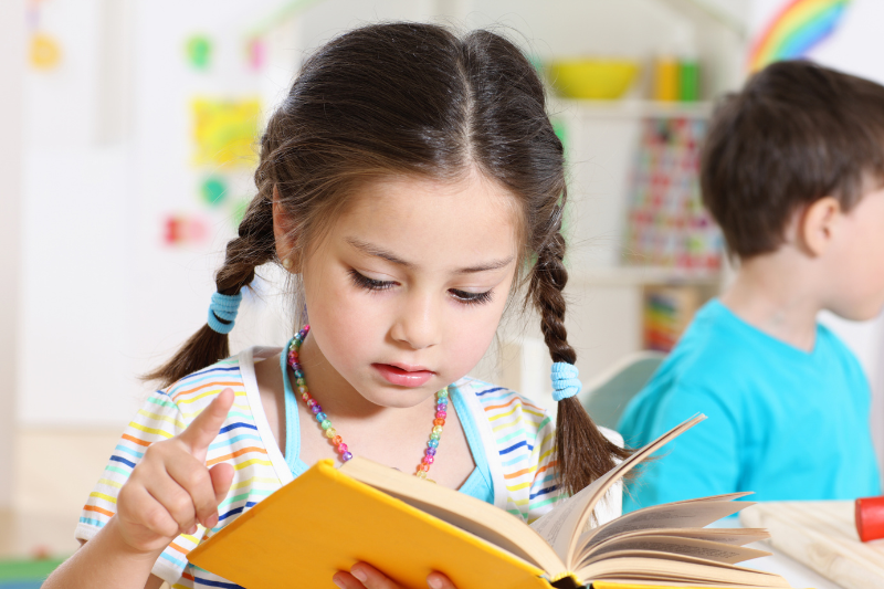 Girl reading a book as part of a homeschool activity focused on teaching rhyming words
